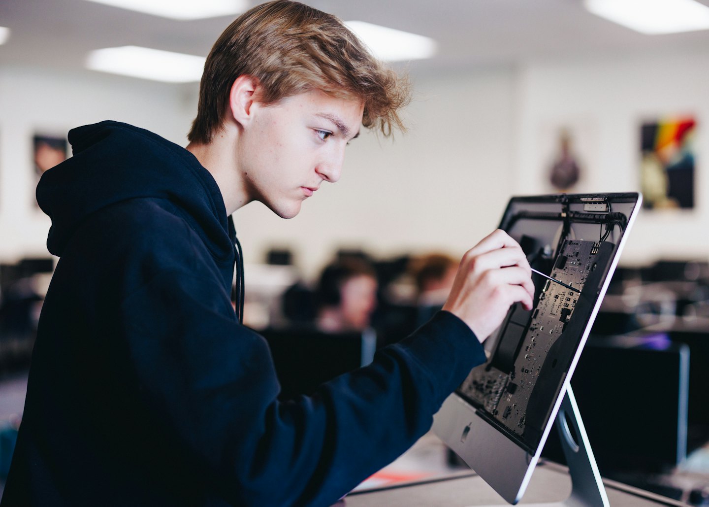 Mann repariert Computerplatine im Klassenraumlabor.