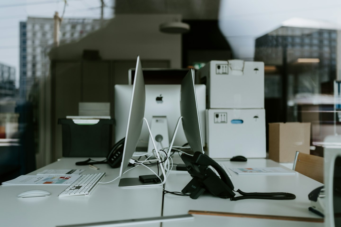 Moderne Bürotische mit Computern und Telefonen in einem Arbeitsbereich.