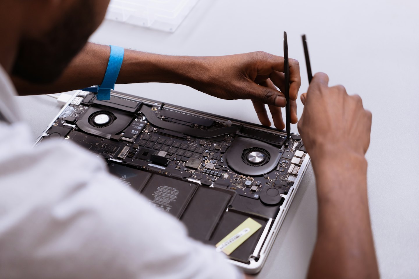 Techniker repariert offenen Laptop mit kleinen Werkzeugen.