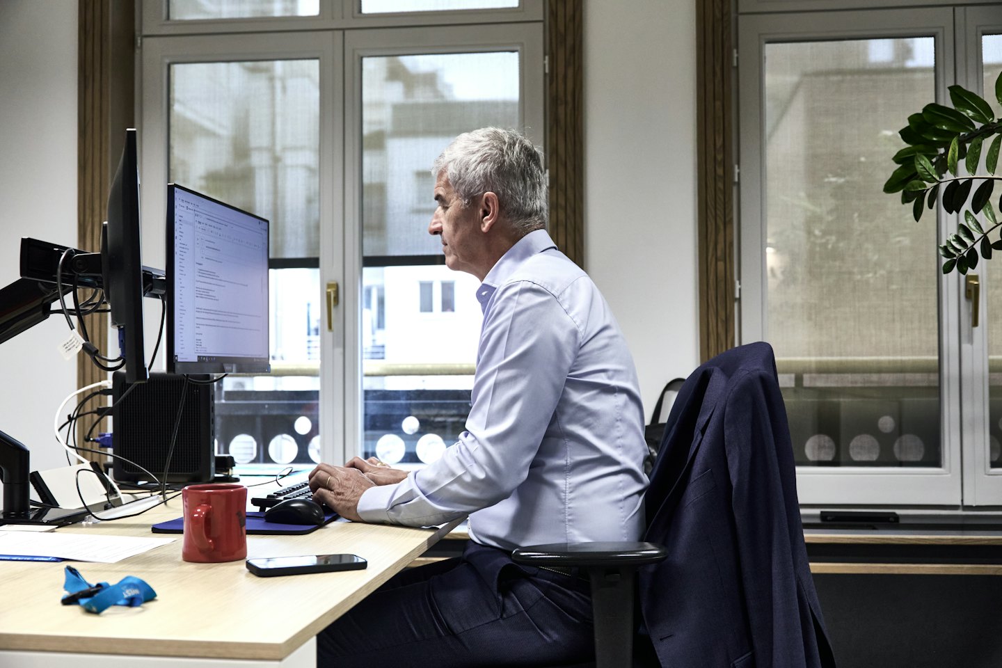 Ein Mann im Hemd tippt an seinem Schreibtisch im Büro auf seinem Computer.
